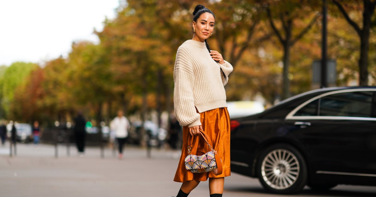 PARIS, FRANCE - SEPTEMBER 28: Tamara Kalinic wears a wool pullover, an orange shiny silky skirt, earrings, a Fendi bag, black high heeled boots, outside CDG Comme des Garçons, during Paris Fashion Week - Womenswear Spring Summer 2020 on September 28, 2019 in Paris, France. (Photo by Edward Berthelot/Getty Images)