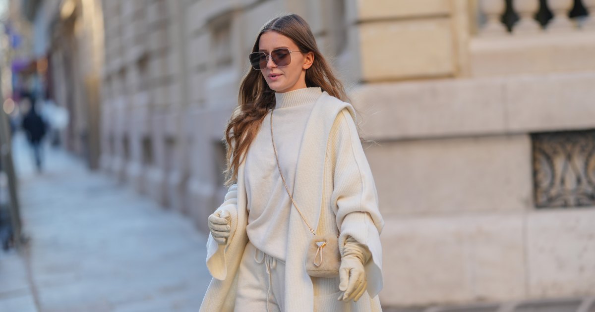 Diane Batoukina wears brown Dior sunglasses, a white cashmere Zara turtleneck pullover, matching coat and pants, a light brown fluffy faux fur Prada bag, white leather gloves, during a street style fashion photo session, on January 13, 2025 in Paris, France.